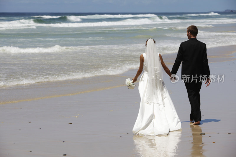 在海滩上散步的新婚夫妇