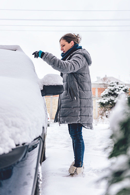 一个女人正在清理一辆被雪覆盖的汽车