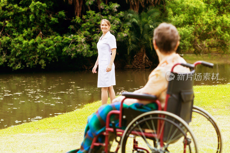 公园里的护理护士对着轮椅上的孩子微笑
