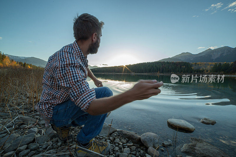 日落时分，湖边的年轻人在抛石子