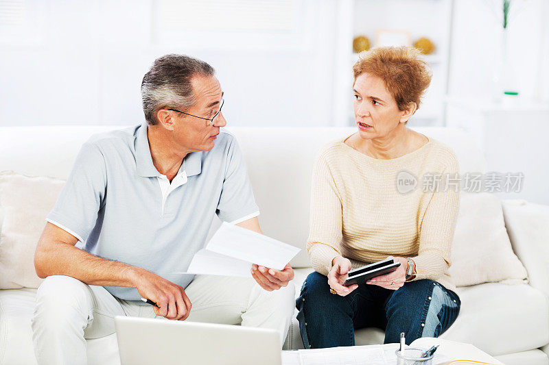 一对老年夫妇在家里计算每月的财务状况。