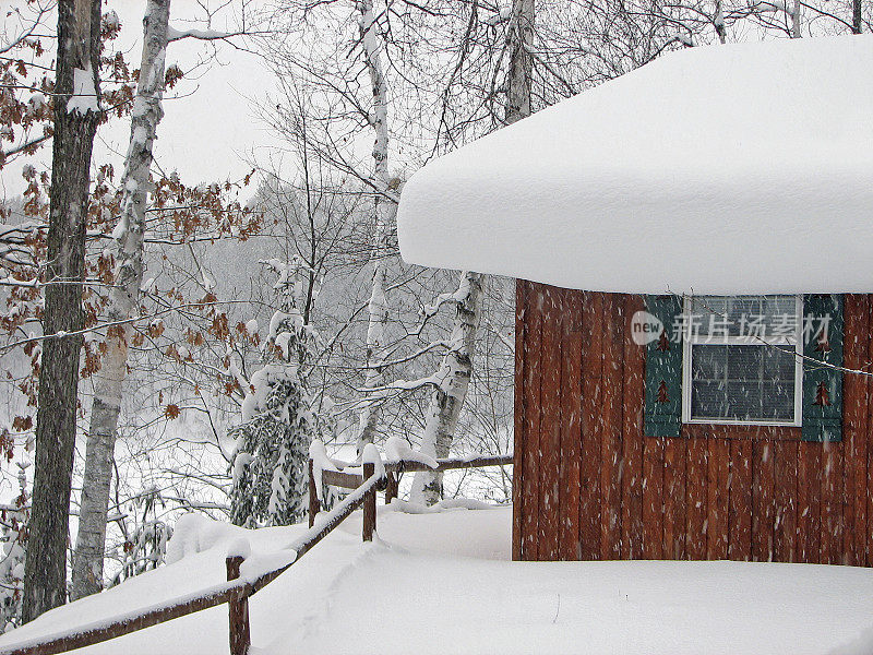 暴风雪期间被雪覆盖的湖边小屋