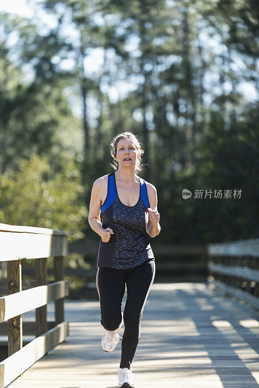 成熟的女人在公园里跑步