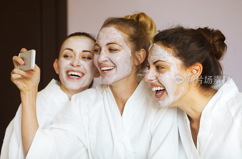 三个年轻快乐的女人戴着面具在温泉度假村。