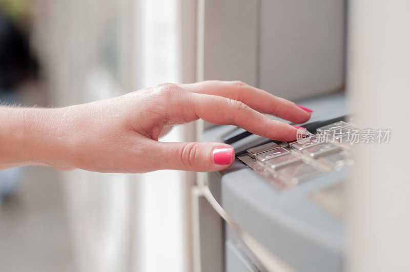 在ATM机输入密码的手的特写。