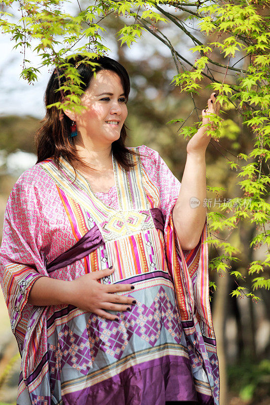 孕妇抱着肚子看着叶子