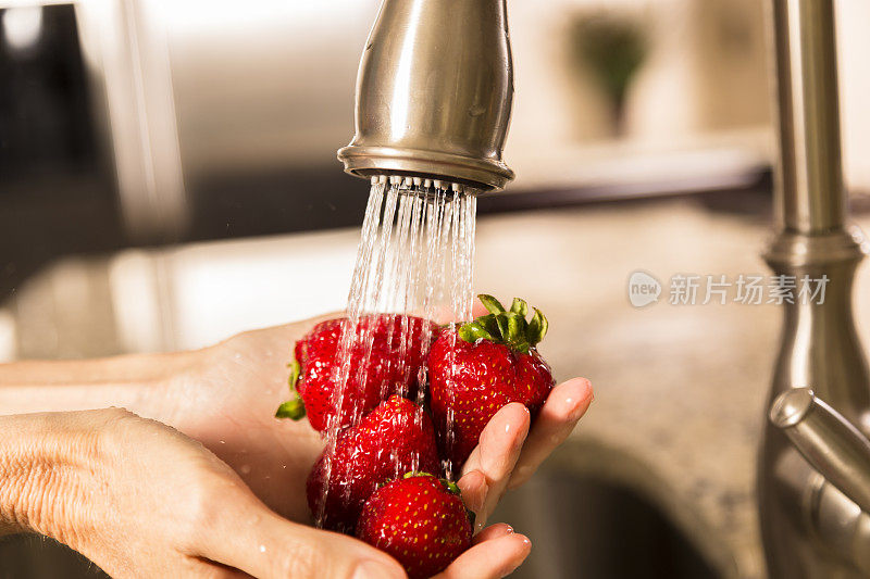 食物:在水槽洗草莓的女人。