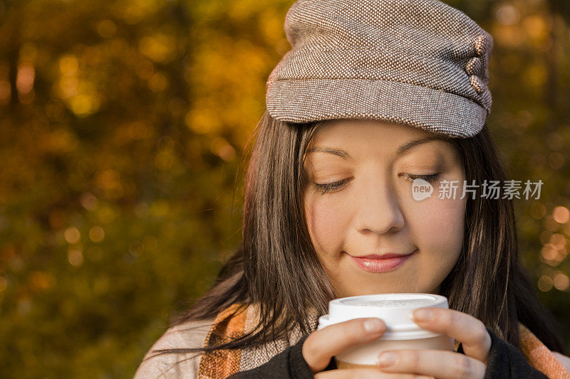 饮料:年轻女子手持热咖啡在秋天。