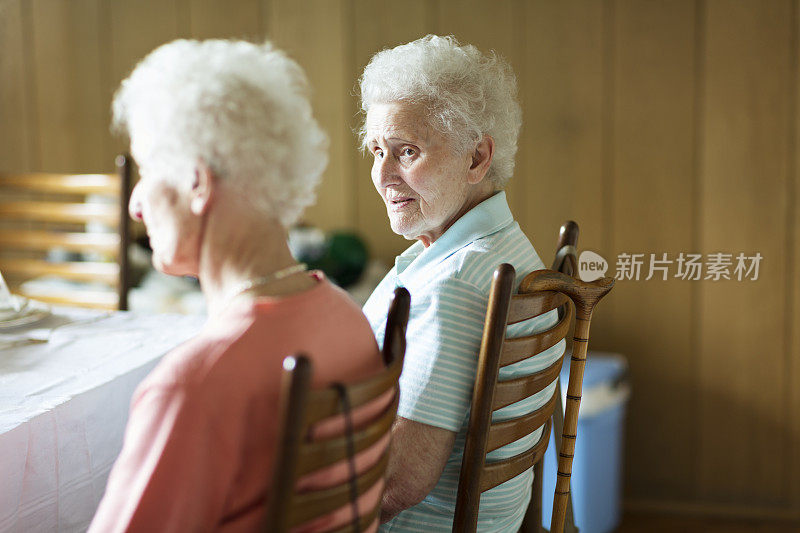 两位资深女性在餐桌上聊得很开心