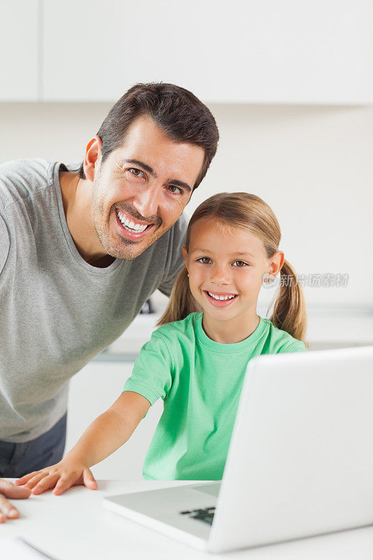 父亲和女儿在用笔记本电脑