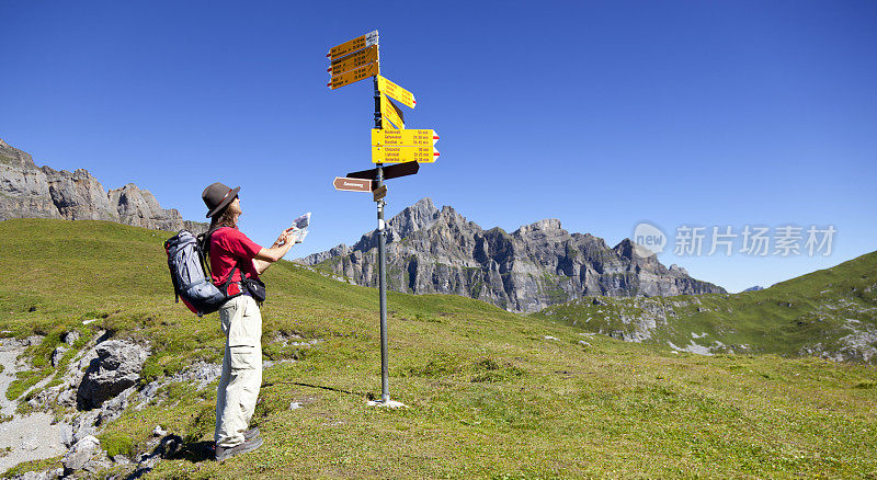 在瑞士山区阅读地图和唱歌的徒步旅行者
