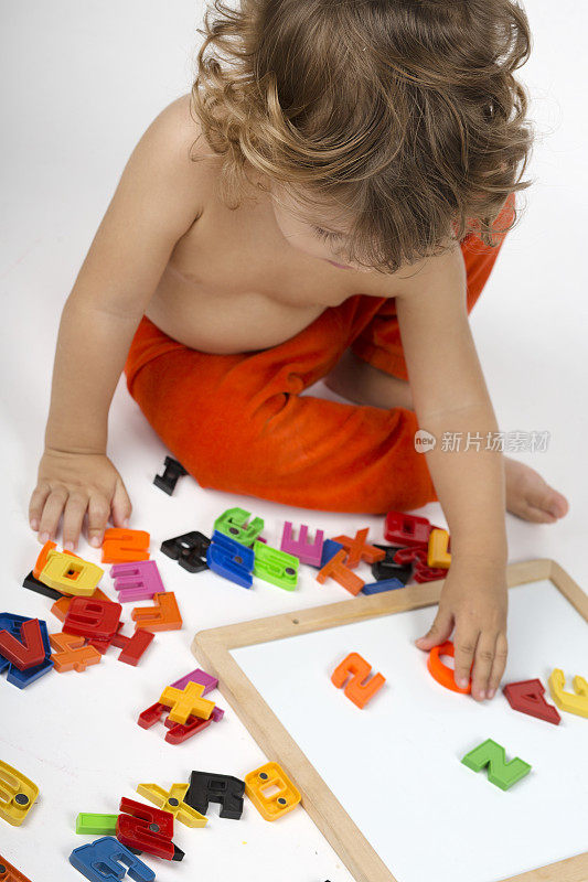 小男孩在玩五颜六色的字母