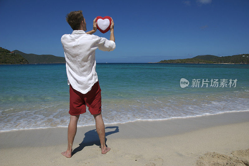 热带海滩上的男人把心放在天空中