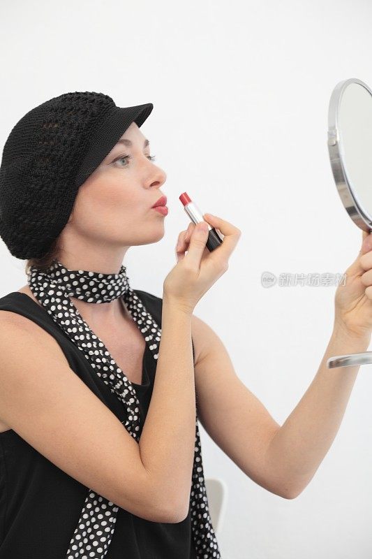 复古风格的女人是看着镜子，涂着嘴唇。