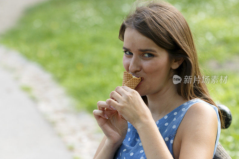 一个漂亮的女孩坐在公园里吃冰淇淋