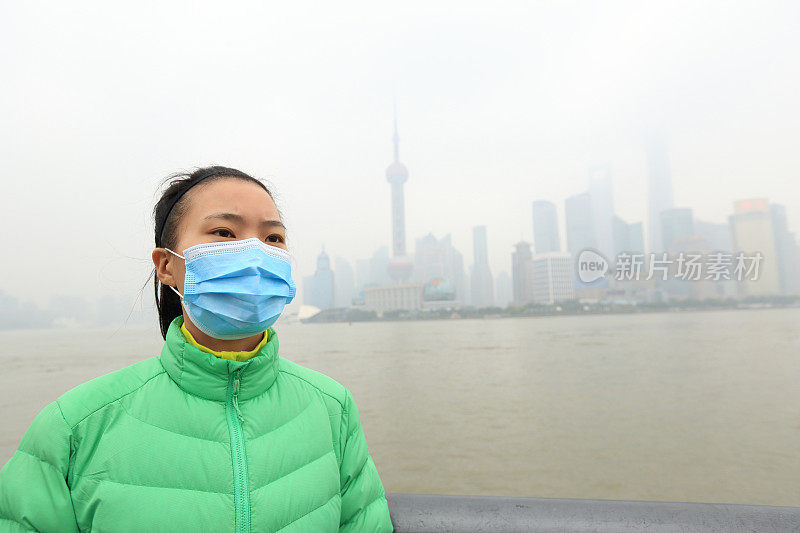 忧心忡忡的年轻女子在污染严重的城市里戴着口罩