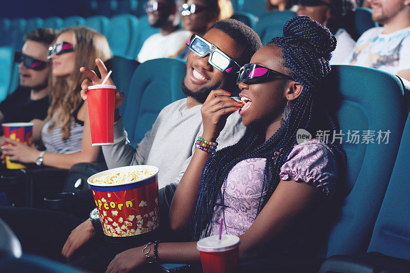 两个非洲人在电影院吃爆米花，喝可乐。