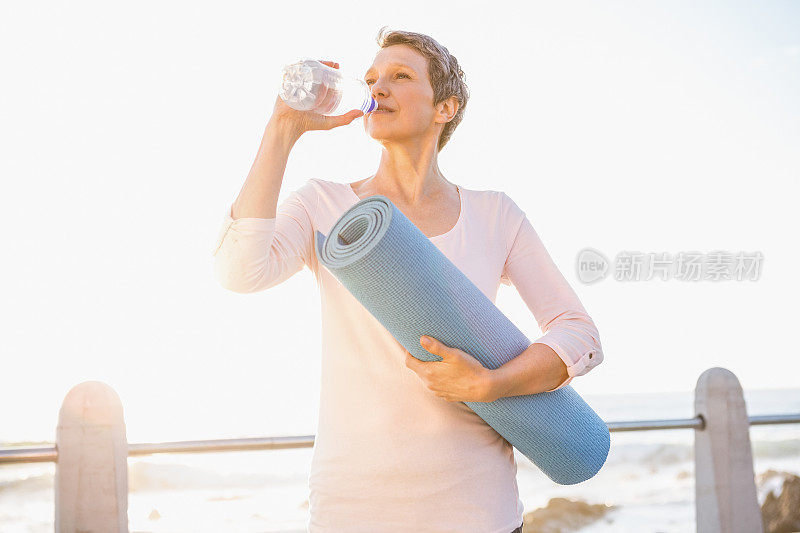 运动女人用运动垫喝水