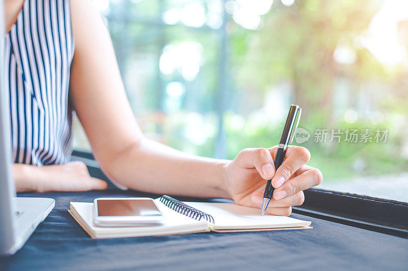 女人在办公室用钢笔在记事本上写字。