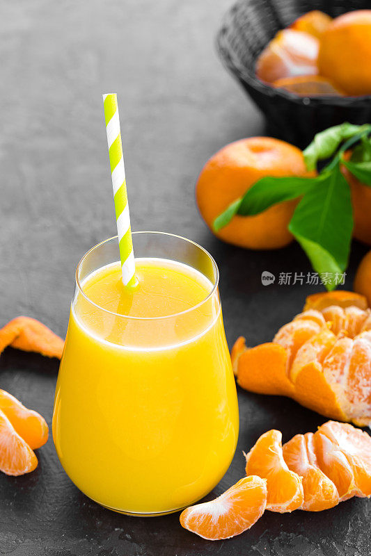 橘子，去皮的橘子和橘子汁在玻璃杯里。橘子汁和带叶子的新鲜水果。