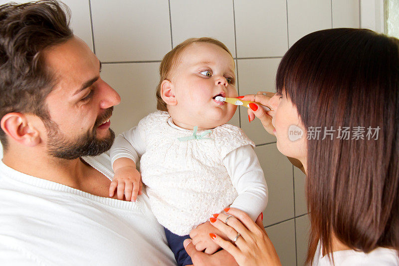 妈妈和爸爸在给他们的宝宝刷牙