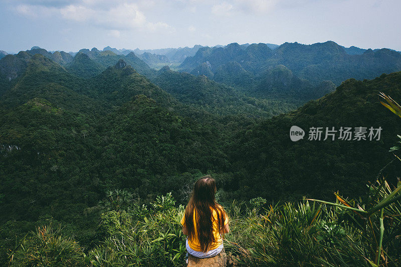 一名女子在山顶休息，欣赏越南吉巴岛的丛林景色