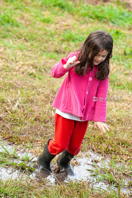 小女孩穿着雨靴在泥地里玩耍