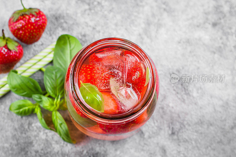 夏季食物和饮料。水泥桌上放着一瓶草莓罗勒柠檬水。本空间