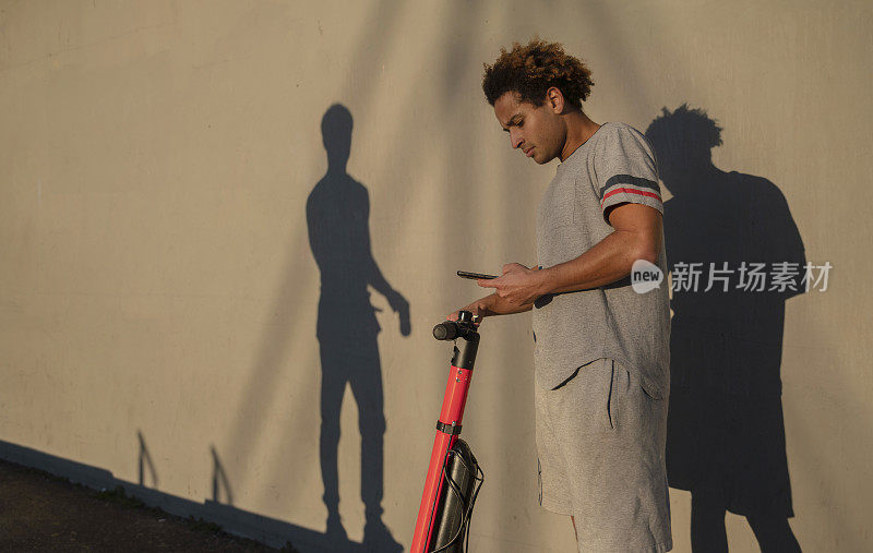 在美国加州威尼斯海滩，这位年轻的拉丁裔男子用他的智能手机预订了电动滑板车