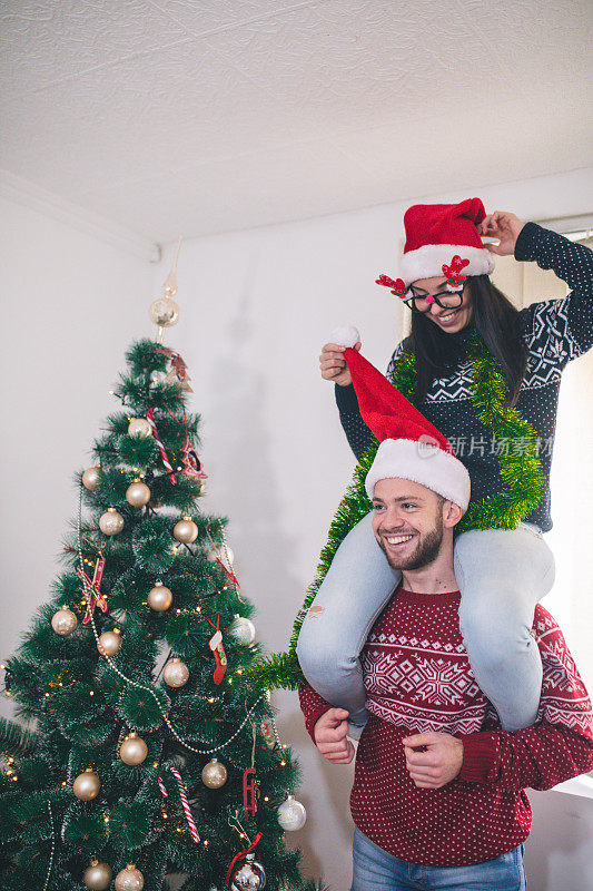 可爱的年轻夫妇装饰圣诞树