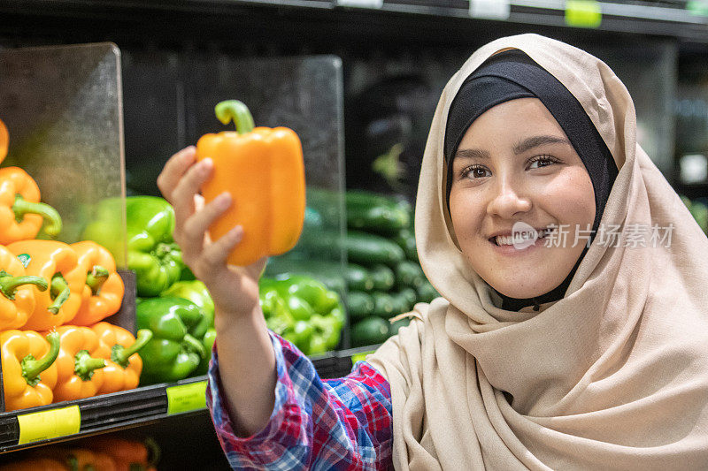 微笑的年轻穆斯林妇女购买蔬菜