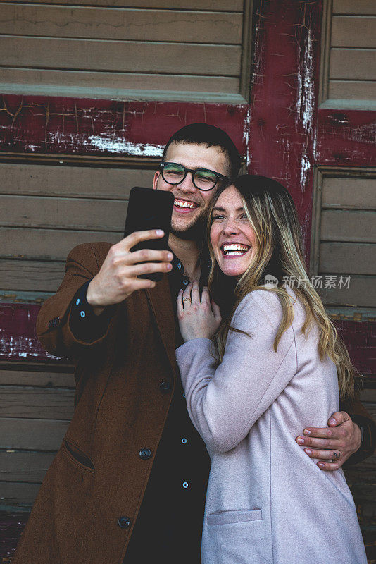 20多岁的潮情侣在用智能手机自拍
