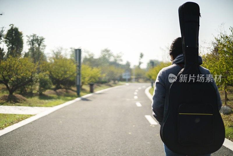 女孩拿着吉他走在路上