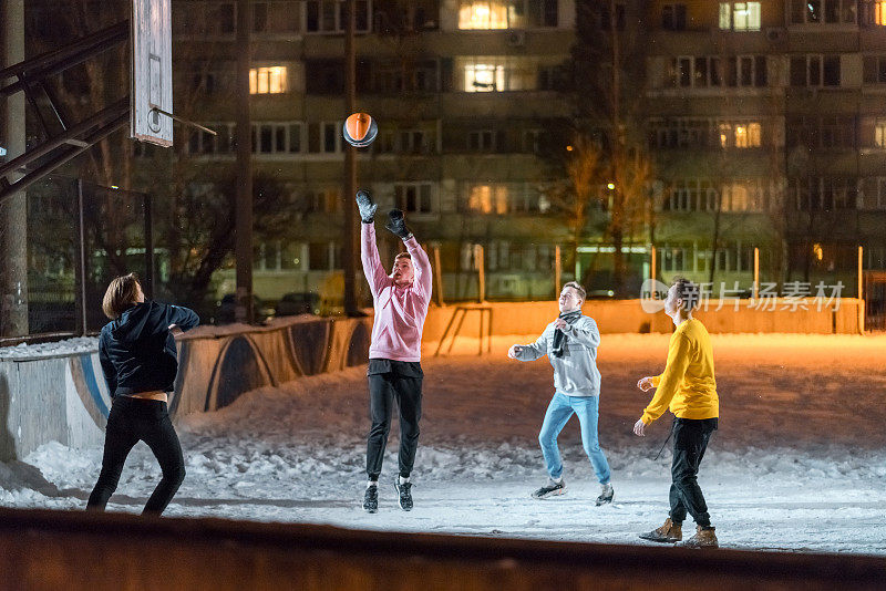 年轻人在白雪覆盖的操场上打篮球
