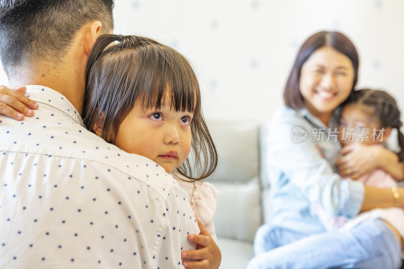 悲伤和哭泣的亚洲女孩被他们的父母安慰