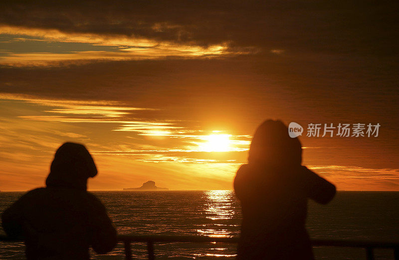 南极泻湖上的日落与漂流的冰山和雪峰的背景，勒梅尔海峡，南极洲