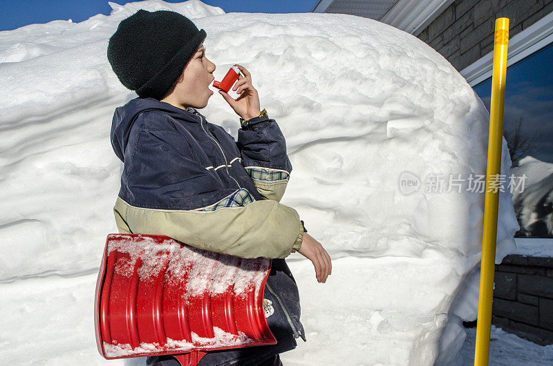 小男孩在铲雪后使用哮喘泵