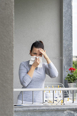 有过敏症的年轻女子在阳台上晾湿衣服