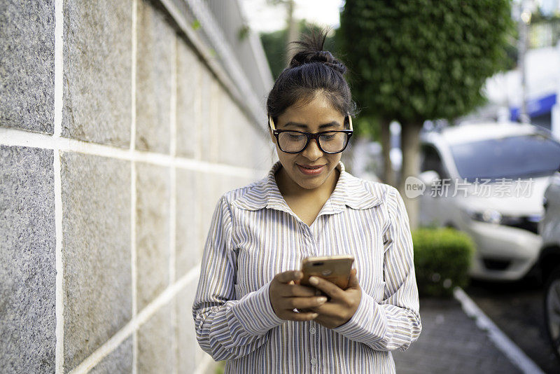 一个拉丁女人在街上走的时候用着智能手机