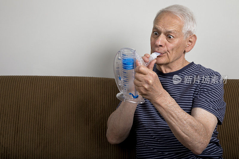 老人在家里用肺活量计用力观察进展