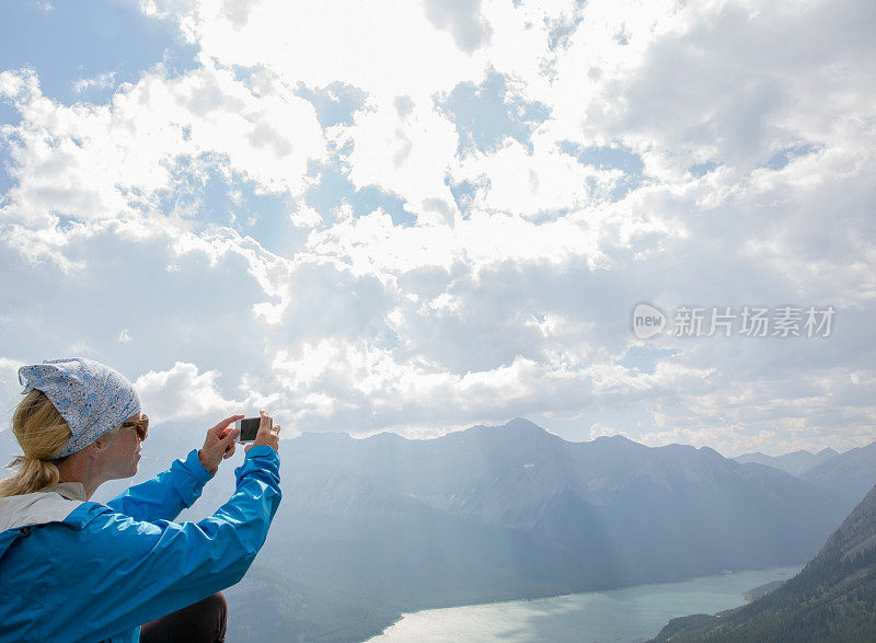 女徒步旅行者从山顶拍摄湖泊和阳光