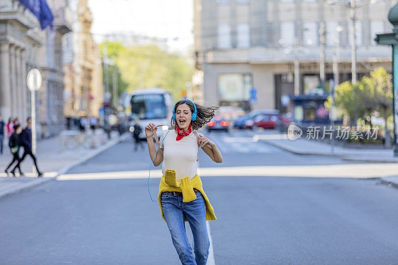 街上的年轻女子正在听音乐和跳舞