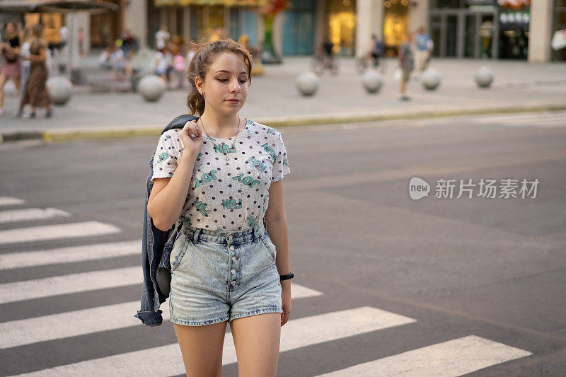 十几岁的女孩过马路。前视图照片