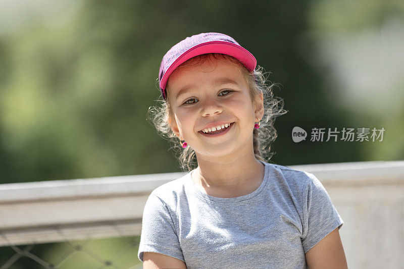 带着棒球帽微笑的可爱小女孩
