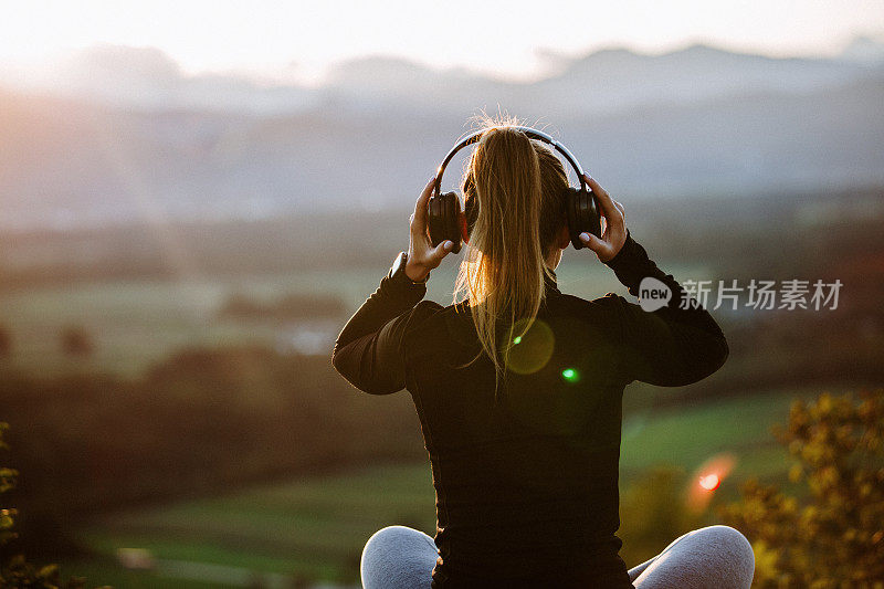 女孩戴着耳机在夕阳下听音乐