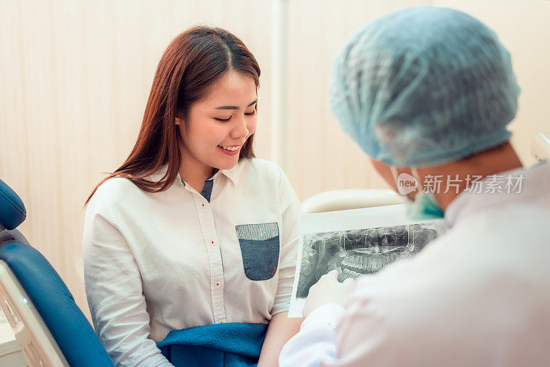 资深男牙医在牙科诊所与女病人谈话，准备治疗。