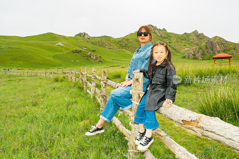 母亲和女儿坐在木栅栏上