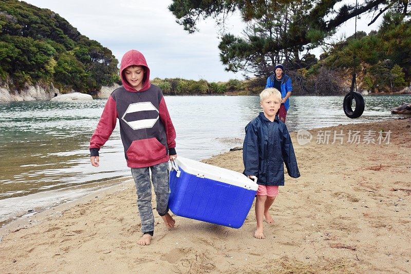 在海岸钓鱼后，年轻的男孩拿着一盒清凉的鱼