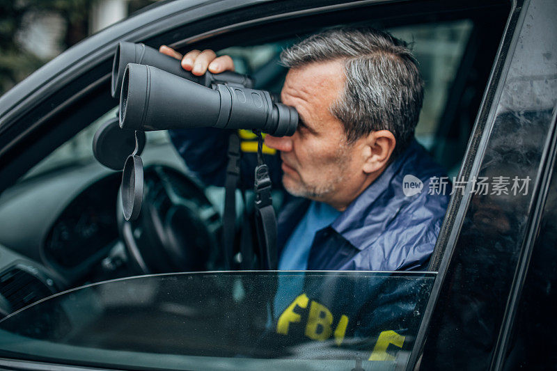 一名联邦调查局探员用望远镜监视他的汽车