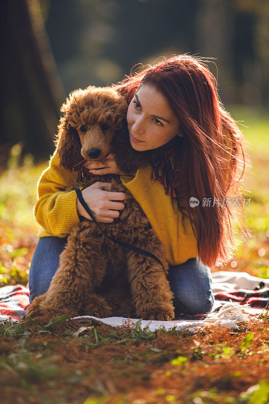 微笑的年轻女子拥抱她的贵宾犬